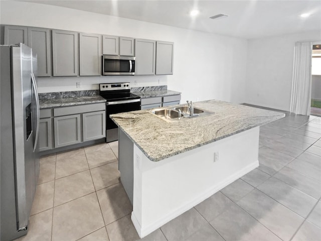 kitchen with appliances with stainless steel finishes, a sink, gray cabinetry, and light tile patterned floors