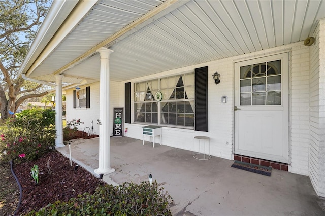 doorway to property featuring covered porch and brick siding