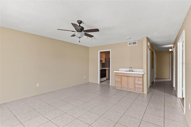 spare room featuring light tile patterned floors, ceiling fan, visible vents, and a textured ceiling