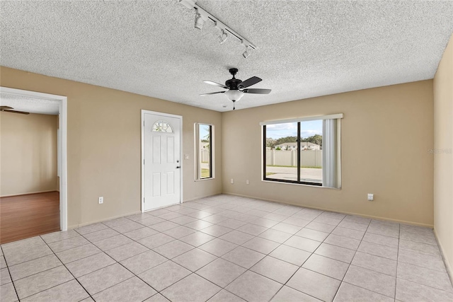 spare room with ceiling fan, light tile patterned floors, and a textured ceiling