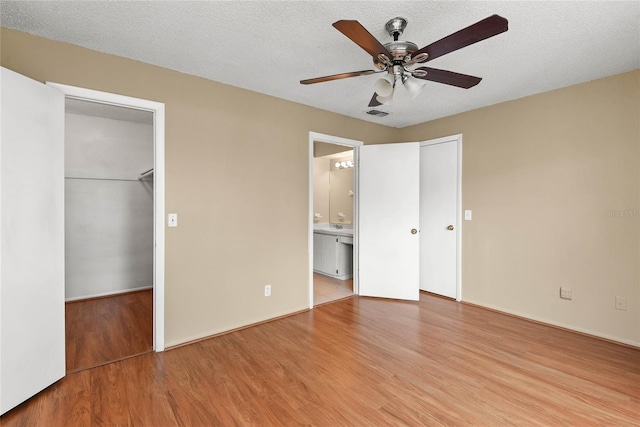 unfurnished bedroom with a textured ceiling, visible vents, and wood finished floors