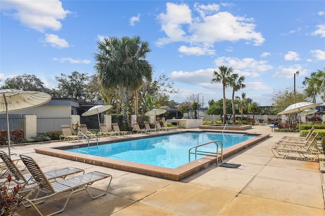 community pool with a patio area and fence