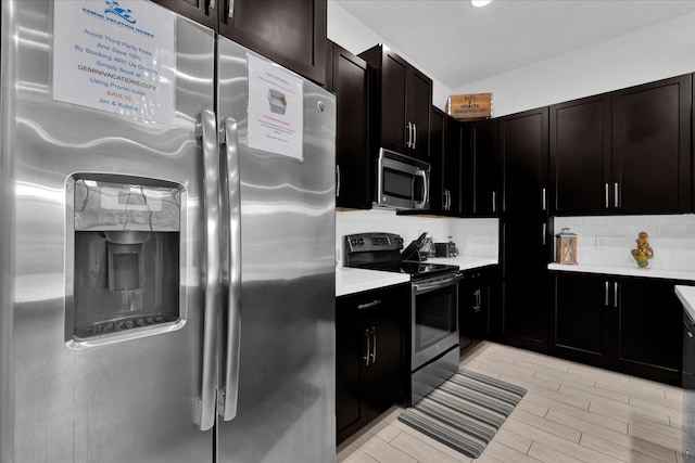 kitchen with backsplash, wood tiled floor, light countertops, vaulted ceiling, and appliances with stainless steel finishes