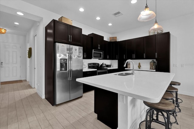 kitchen with light wood-type flooring, a sink, a kitchen breakfast bar, stainless steel appliances, and light countertops