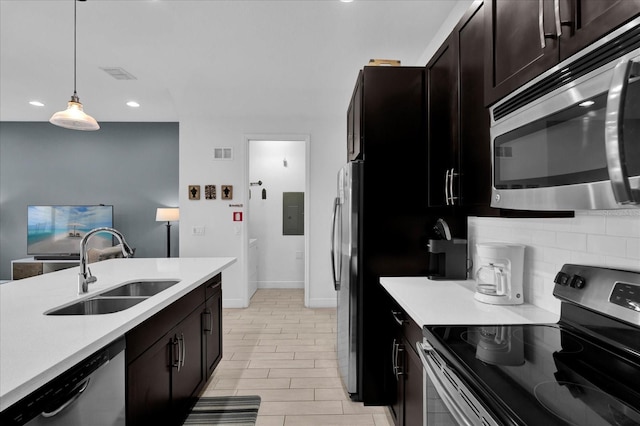 kitchen with a sink, stainless steel appliances, light countertops, decorative light fixtures, and tasteful backsplash