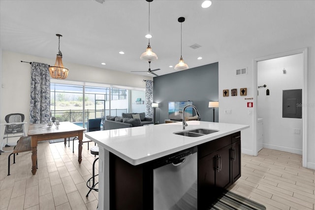 kitchen with electric panel, an island with sink, a sink, light countertops, and stainless steel dishwasher