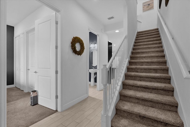 staircase with wood finished floors, visible vents, and baseboards