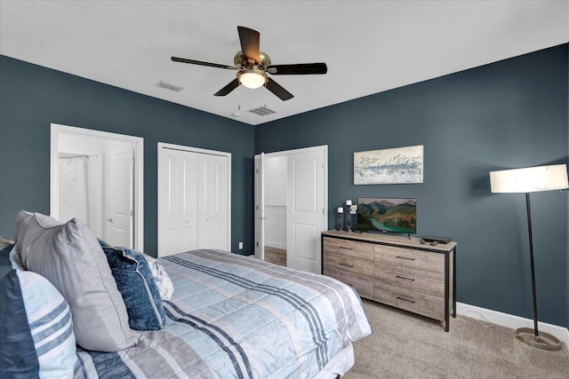 bedroom featuring ceiling fan, multiple closets, visible vents, and light carpet