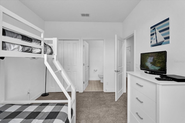 carpeted bedroom featuring visible vents, connected bathroom, and baseboards