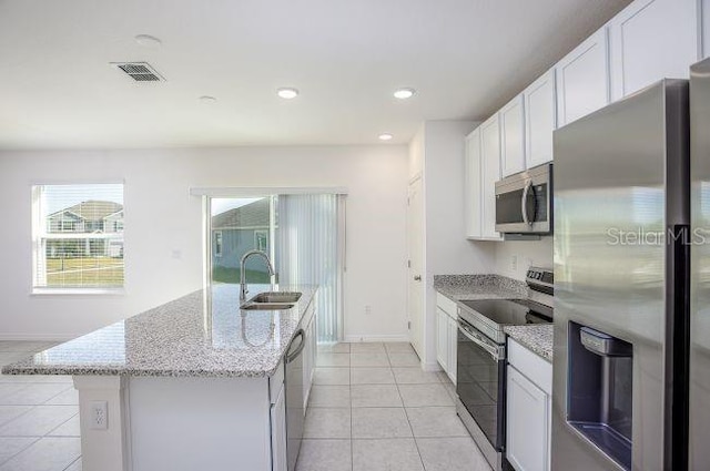 kitchen with light tile patterned flooring, a sink, visible vents, appliances with stainless steel finishes, and a center island with sink