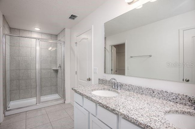 full bathroom featuring double vanity, a stall shower, and a sink