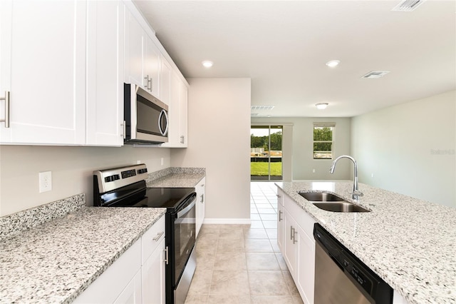 kitchen with visible vents, appliances with stainless steel finishes, light stone counters, white cabinetry, and a sink