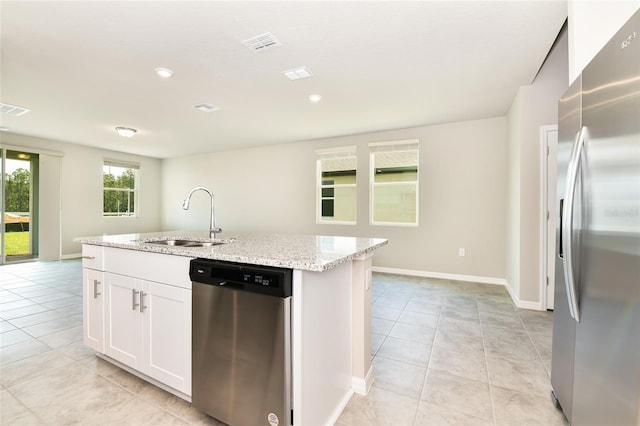 kitchen with a kitchen island with sink, a sink, visible vents, appliances with stainless steel finishes, and light stone countertops