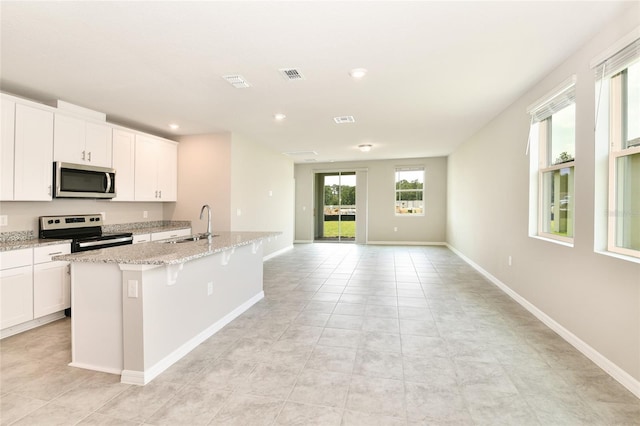 kitchen featuring visible vents, white cabinets, appliances with stainless steel finishes, a kitchen island with sink, and a sink