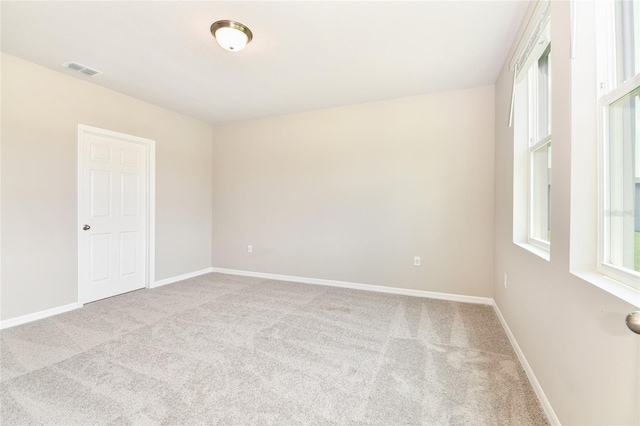 carpeted spare room with visible vents and baseboards