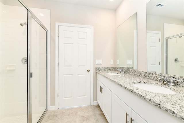 full bath with visible vents, a sink, a shower stall, and double vanity