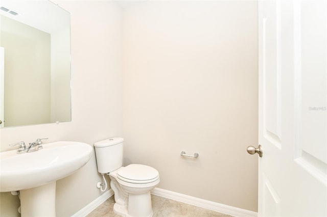 bathroom featuring visible vents, toilet, a sink, baseboards, and tile patterned floors