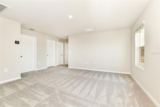 spare room featuring carpet flooring, visible vents, and baseboards