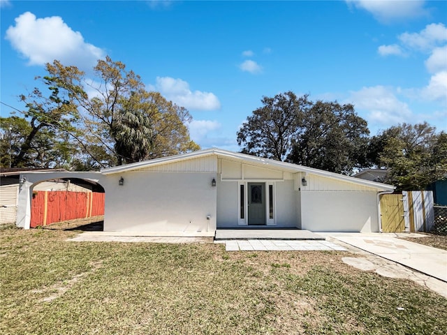 mid-century modern home featuring a front yard, a gate, fence, and stucco siding