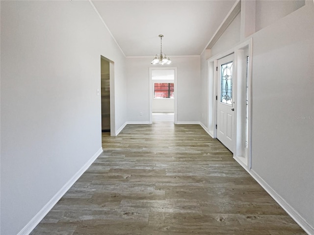 interior space with baseboards, ornamental molding, wood finished floors, and an inviting chandelier