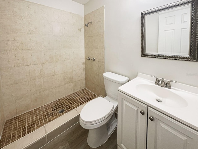 bathroom with tiled shower, vanity, toilet, and wood finished floors