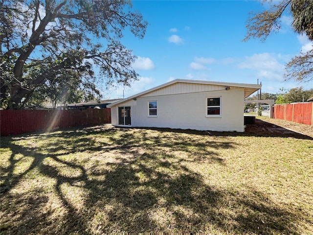 rear view of house featuring a yard, a fenced backyard, and central air condition unit