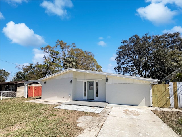 mid-century modern home featuring a gate, a patio area, fence, driveway, and a front lawn