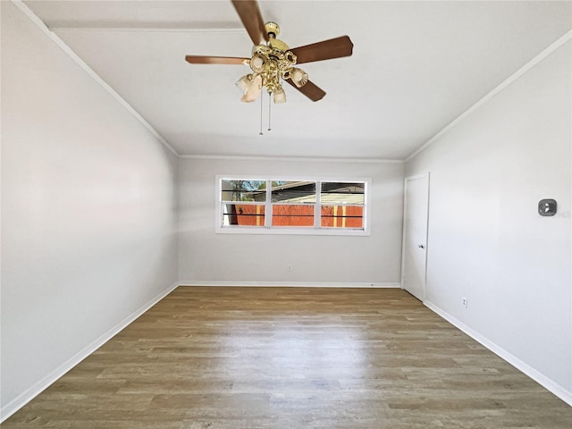 spare room featuring ornamental molding, baseboards, and wood finished floors