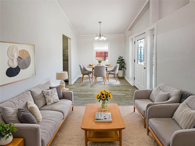 living area featuring lofted ceiling, crown molding, a chandelier, and wood finished floors