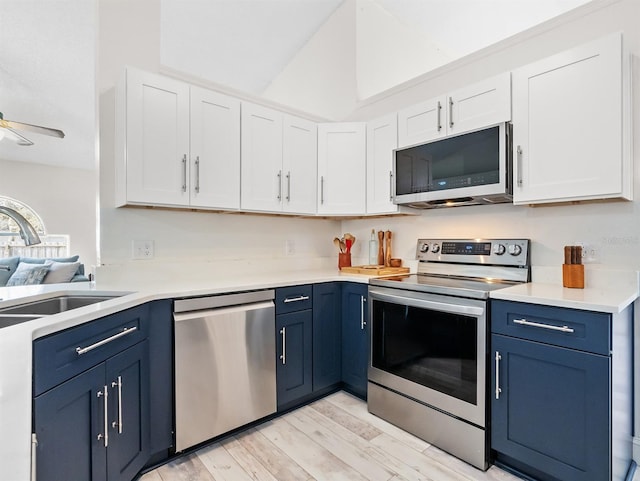 kitchen with stainless steel appliances, a sink, white cabinetry, and blue cabinets