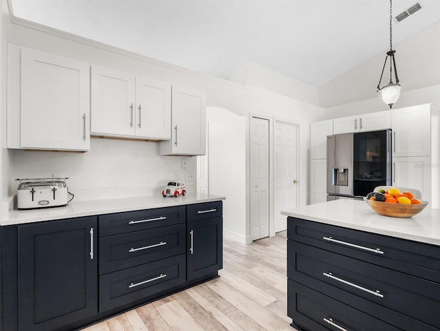 kitchen featuring light wood finished floors, stainless steel fridge, visible vents, white cabinets, and light countertops