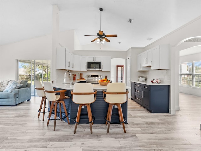 kitchen with arched walkways, stainless steel appliances, a kitchen bar, and visible vents