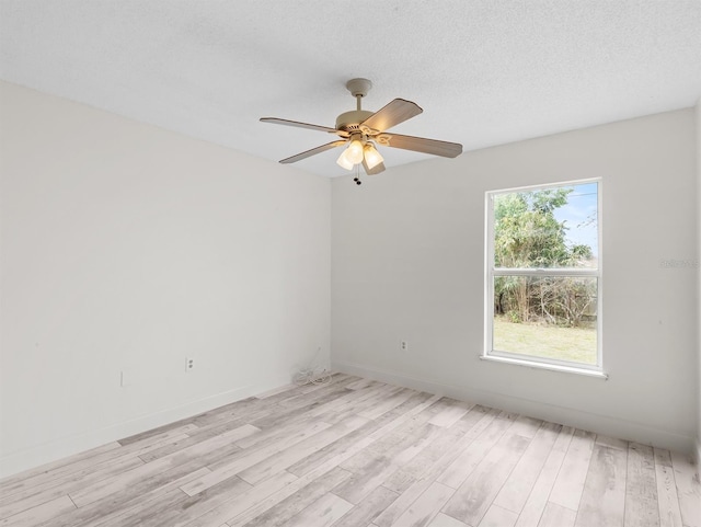 empty room with a ceiling fan, light wood-type flooring, a textured ceiling, and baseboards