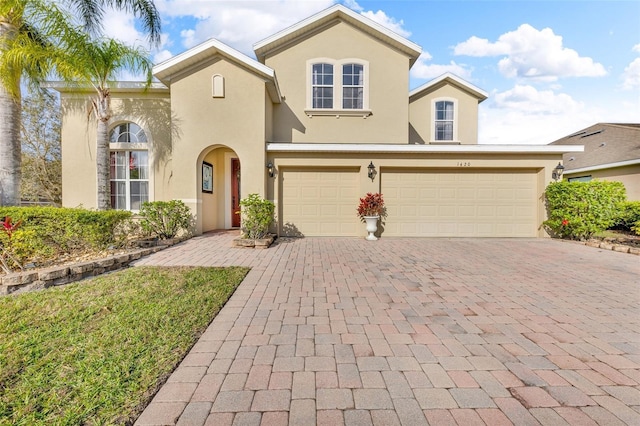 mediterranean / spanish house featuring an attached garage, decorative driveway, and stucco siding