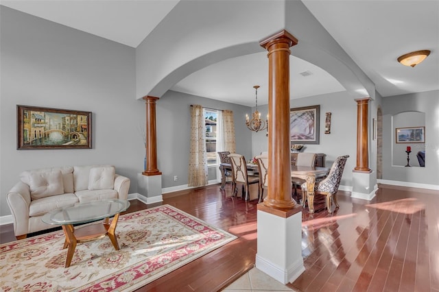 living room with visible vents, arched walkways, baseboards, wood finished floors, and ornate columns