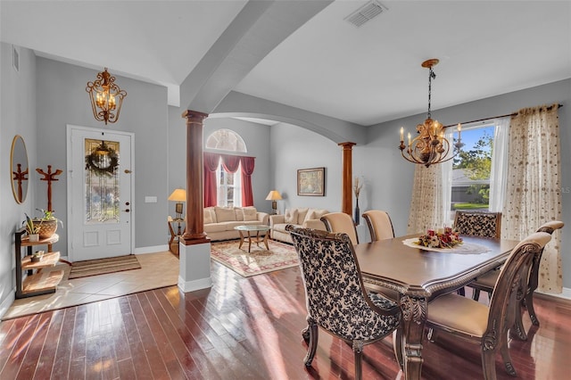 dining room featuring wood finished floors, visible vents, decorative columns, and an inviting chandelier