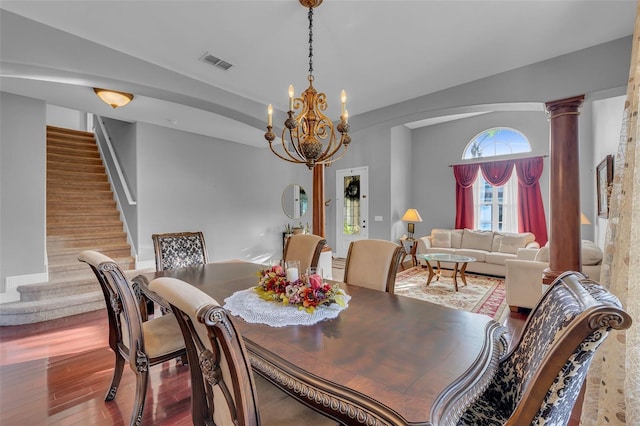 dining room with visible vents, stairway, wood finished floors, vaulted ceiling, and ornate columns