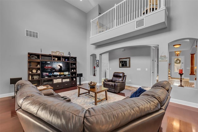 living area featuring arched walkways, visible vents, baseboards, and wood finished floors