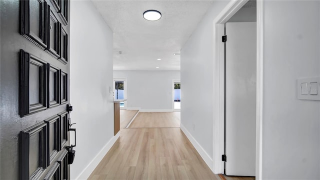 corridor featuring recessed lighting, light wood-type flooring, and baseboards
