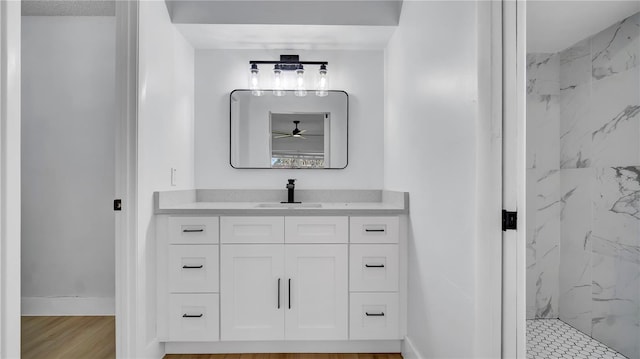 bathroom with baseboards, vanity, a marble finish shower, and wood finished floors