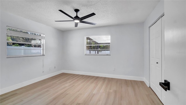 unfurnished bedroom with a textured ceiling, a closet, light wood-type flooring, and baseboards