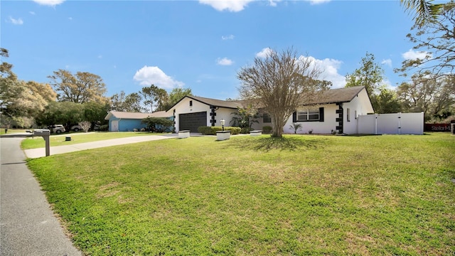ranch-style home with a garage, concrete driveway, a gate, fence, and a front lawn