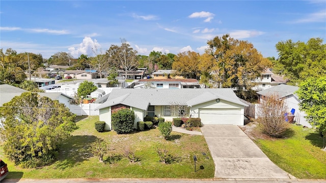 view of front of house featuring a garage, fence, driveway, a residential view, and a front lawn