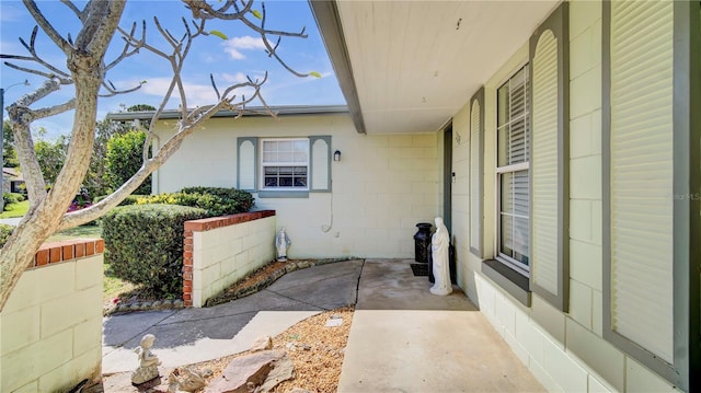 entrance to property with concrete block siding and a patio