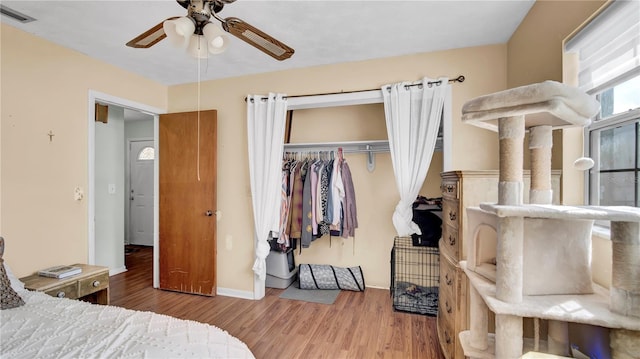 bedroom featuring baseboards, visible vents, ceiling fan, wood finished floors, and a closet