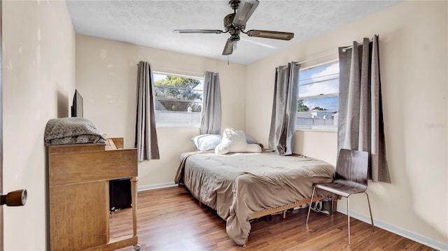 bedroom with a textured ceiling, baseboards, and wood finished floors