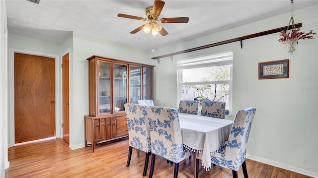 dining room with a ceiling fan, light wood-type flooring, and baseboards