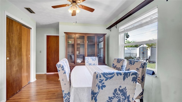 dining room with baseboards, ceiling fan, visible vents, and wood finished floors