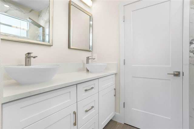 full bath with double vanity, a marble finish shower, and a sink