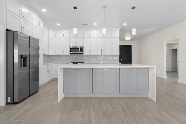 kitchen with stainless steel appliances, light countertops, visible vents, backsplash, and white cabinetry